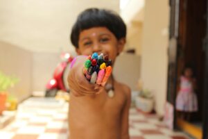 pexels photo 1134168 1134168 A happy child in Hyderabad proudly shows off a handful of vibrant crayons, capturing creativity's joy.