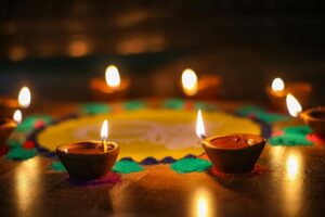 Close-up of lit diyas with festive rangoli, capturing the warm and colorful ambiance of Diwali.